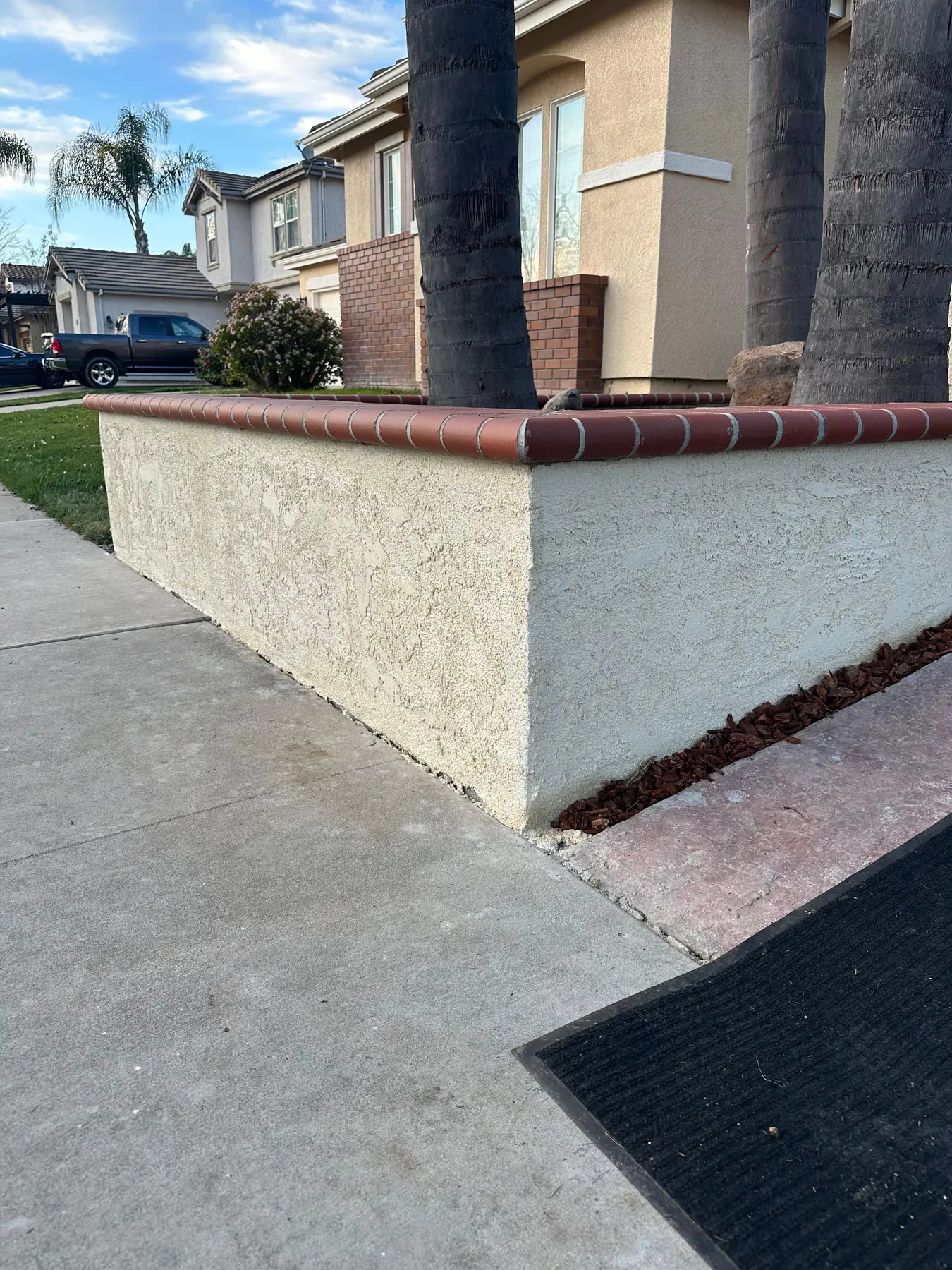 Newly constructed retaining wall with stone blocks and green garden planting, bright daylight, clean open yard